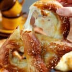 Hands breaking open a pretzel stuffed with cheese