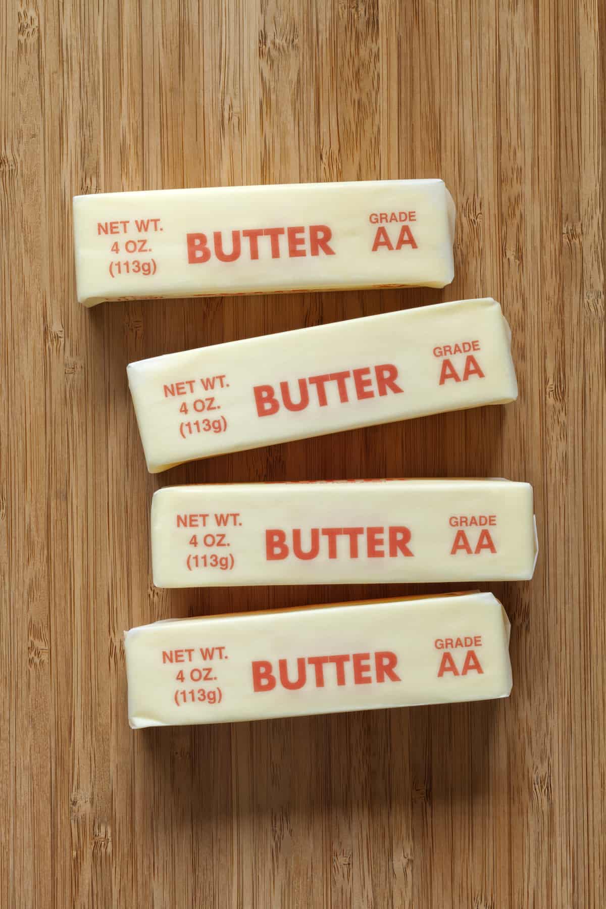 Four quarter pound stick of AA grade butter on a bamboo cutting board.