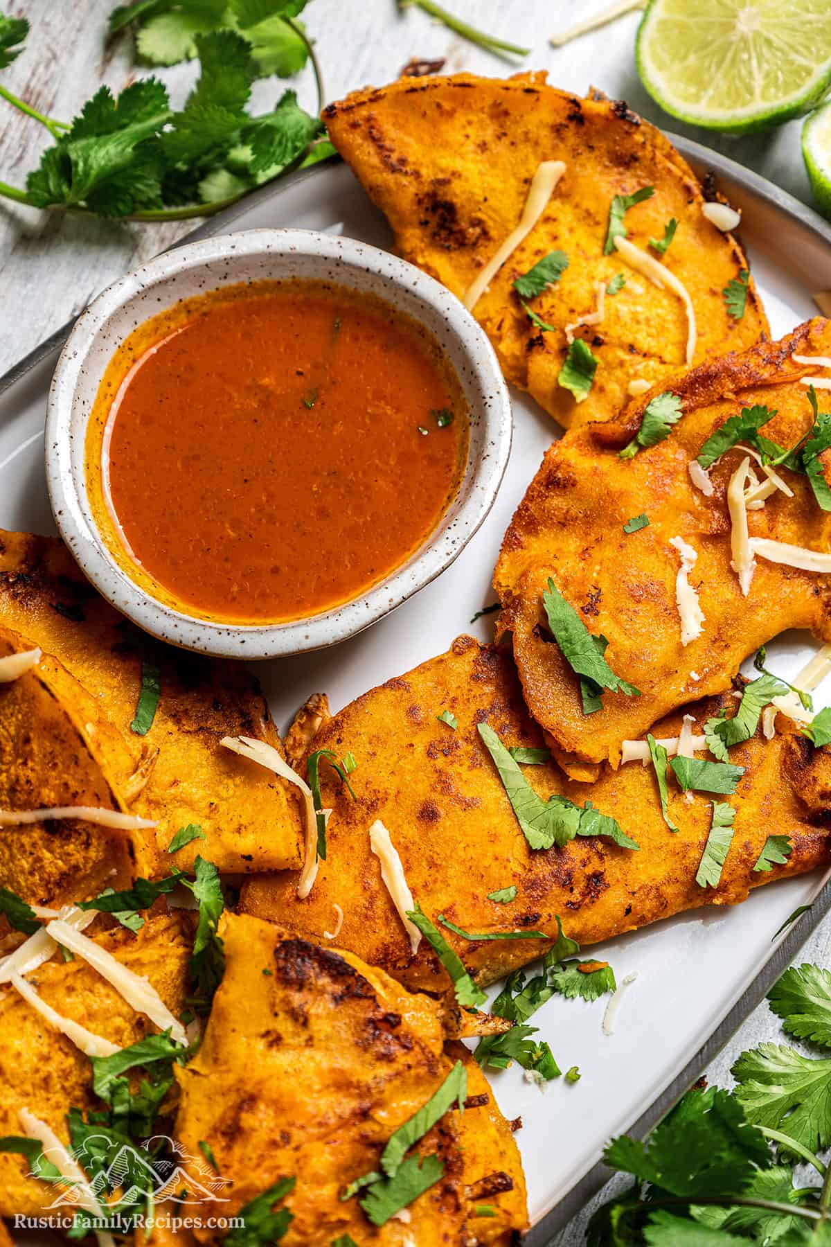 Mexican-style chicken birria tacos made from chicken cooked in a flavorful sauce until fall-apart-tender, fried inside crispy corn tortillas. Overhead view of chicken birria tacos served on a platter next to a bowl of sauce for dipping.