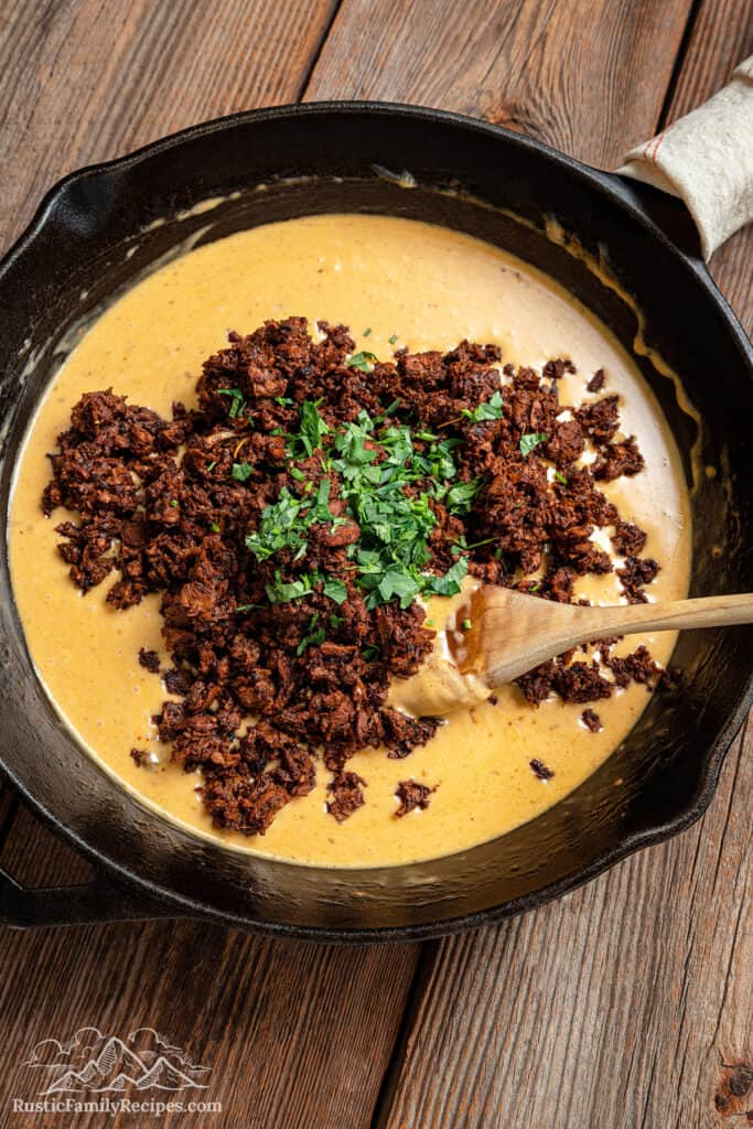 Adding choriqueso to a skillet with melted cheese