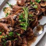 Coulotte steak on a platter topped with buttery mushroom sauce.