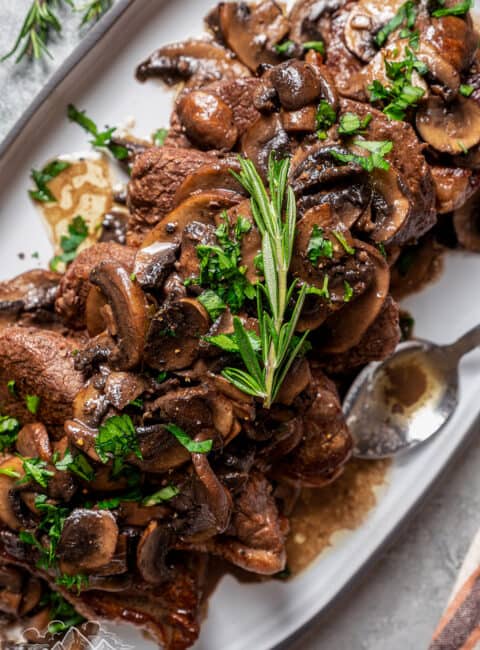 Coulotte steak on a platter topped with buttery mushroom sauce.