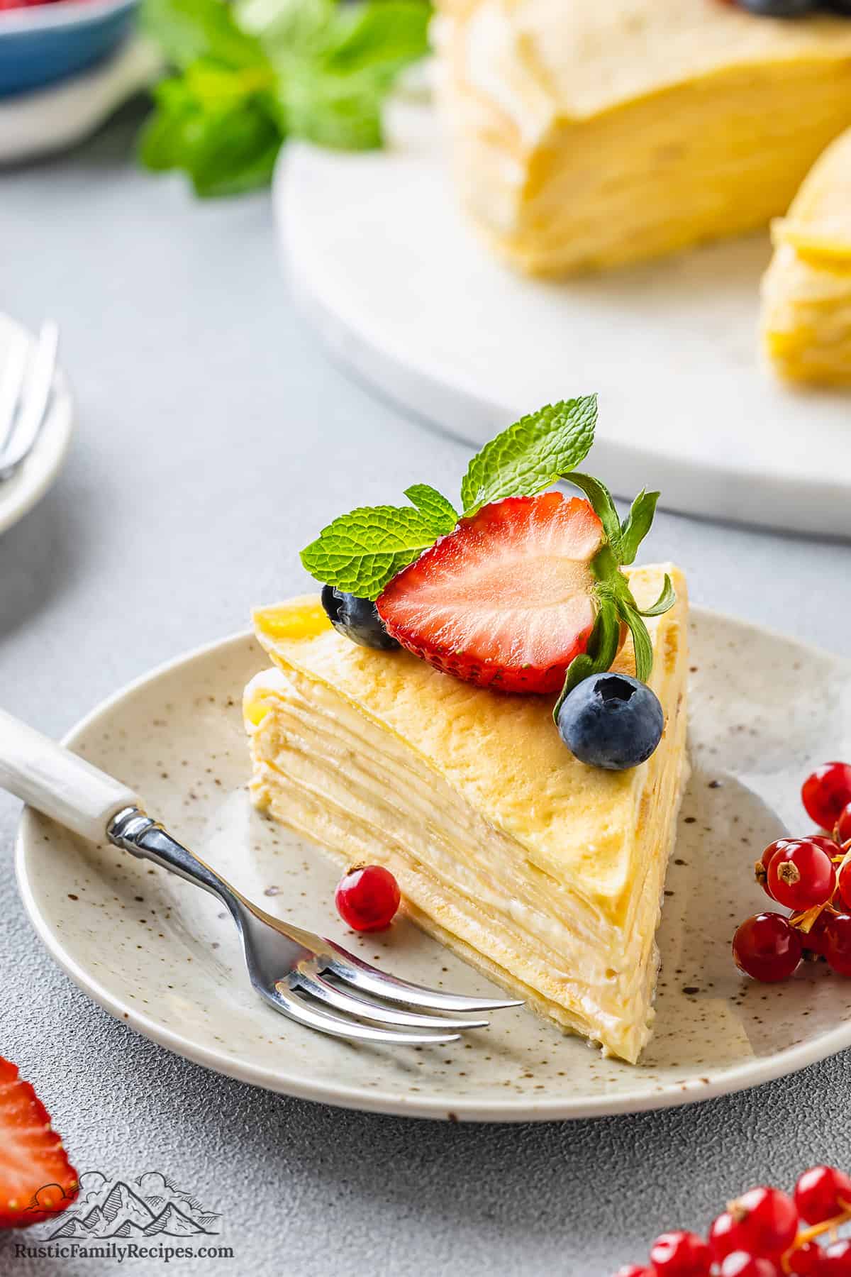 Side view of a slice of Crepe Cake topped with berries.