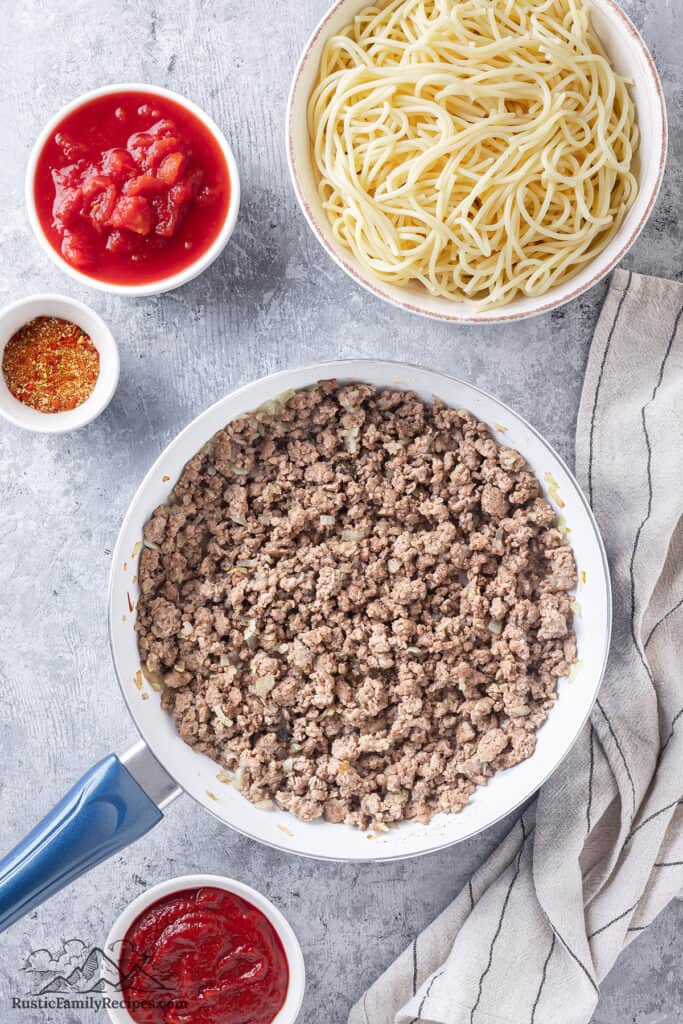 Cooked ground beef in a bowl next to small bowls with sauce ingredients