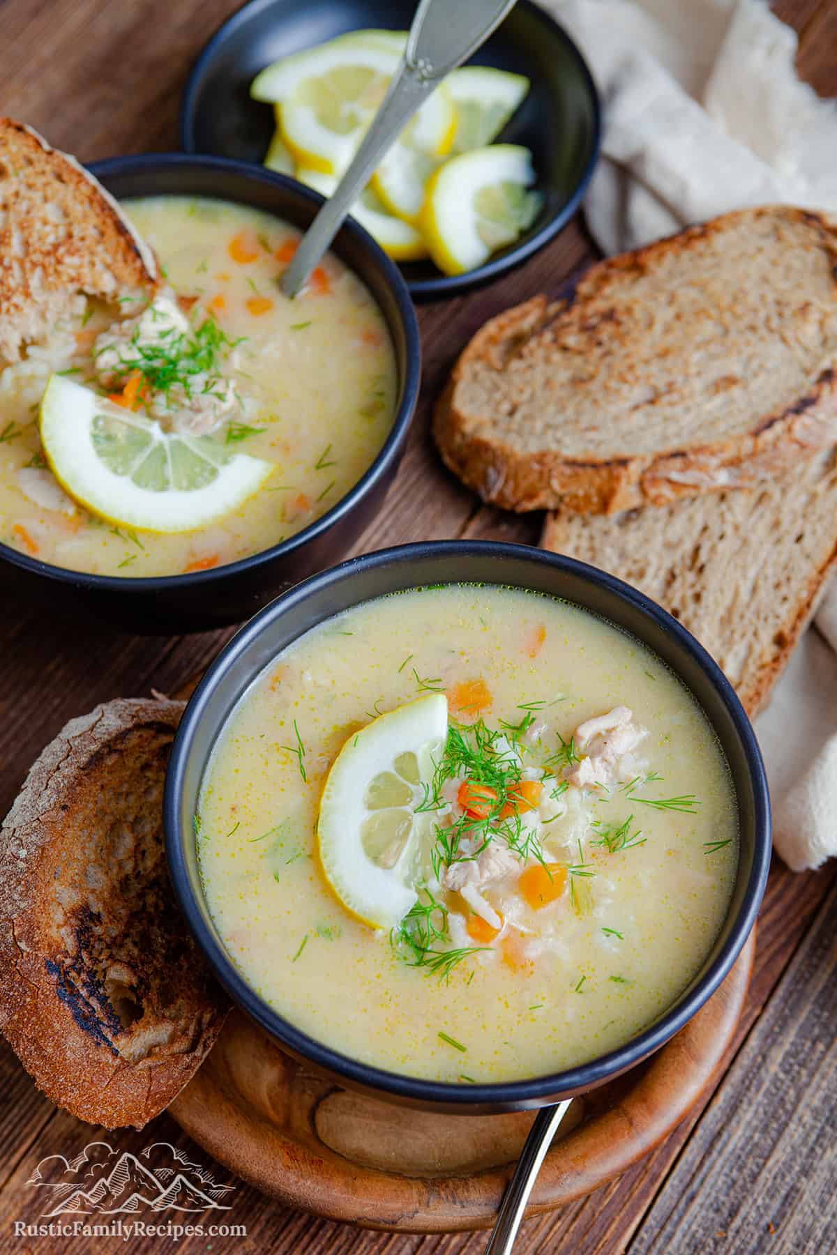 Two bowls of avolemono soup with slices of bread