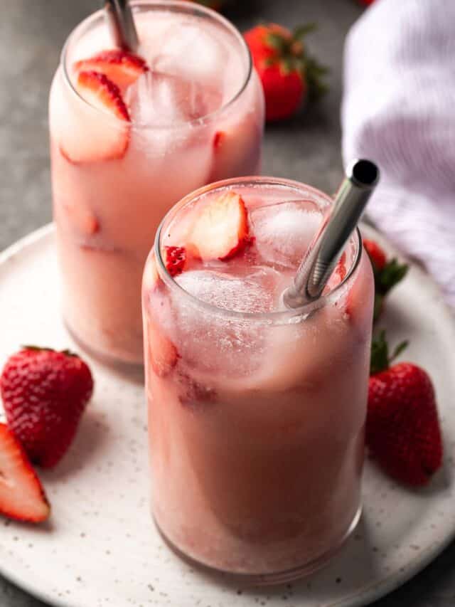 Two pink drinks on a serving plate with strawberry slices
