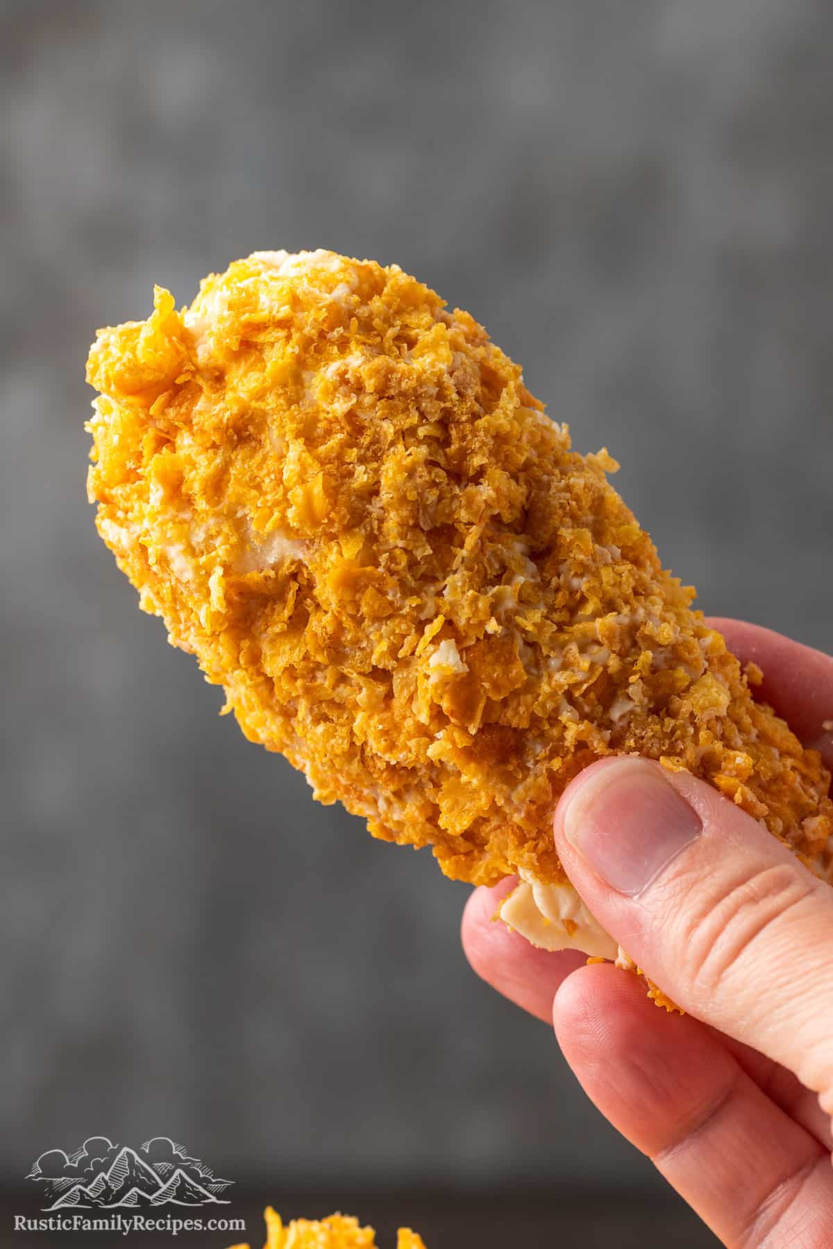 A hand holding a piece of Fried Chicken Ice Cream