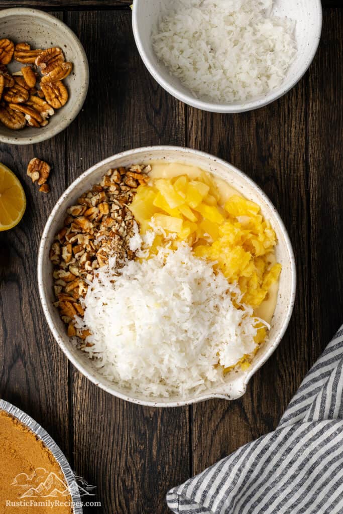 A white bowl with coconut, pecans and pineapple