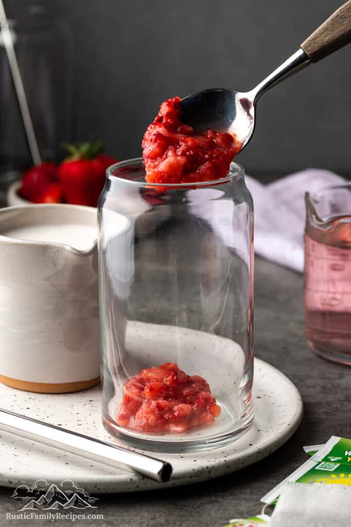 Spooning macerated strawberries into a glass