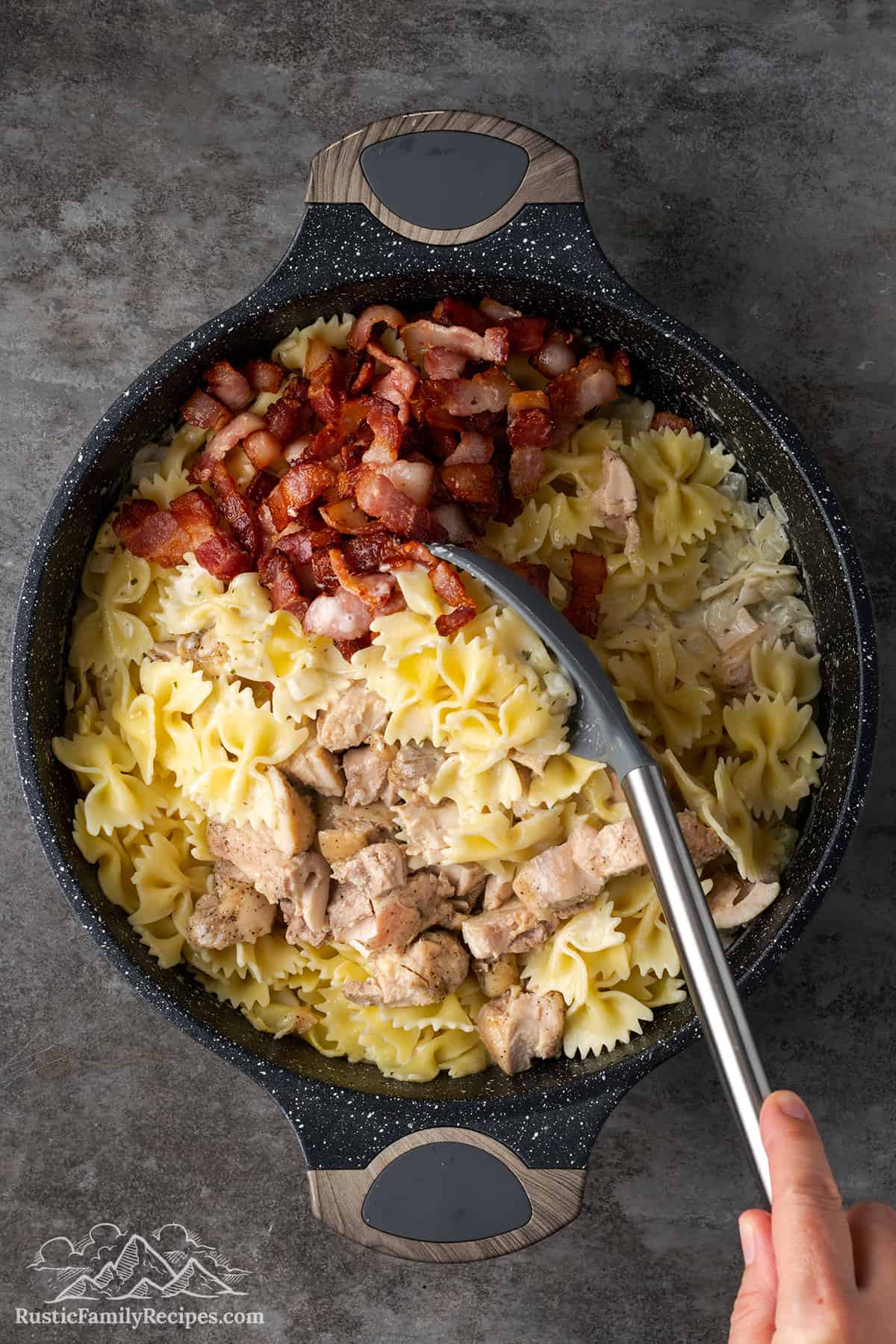Mixing chicken bacon ranch pasta in a deep bowl