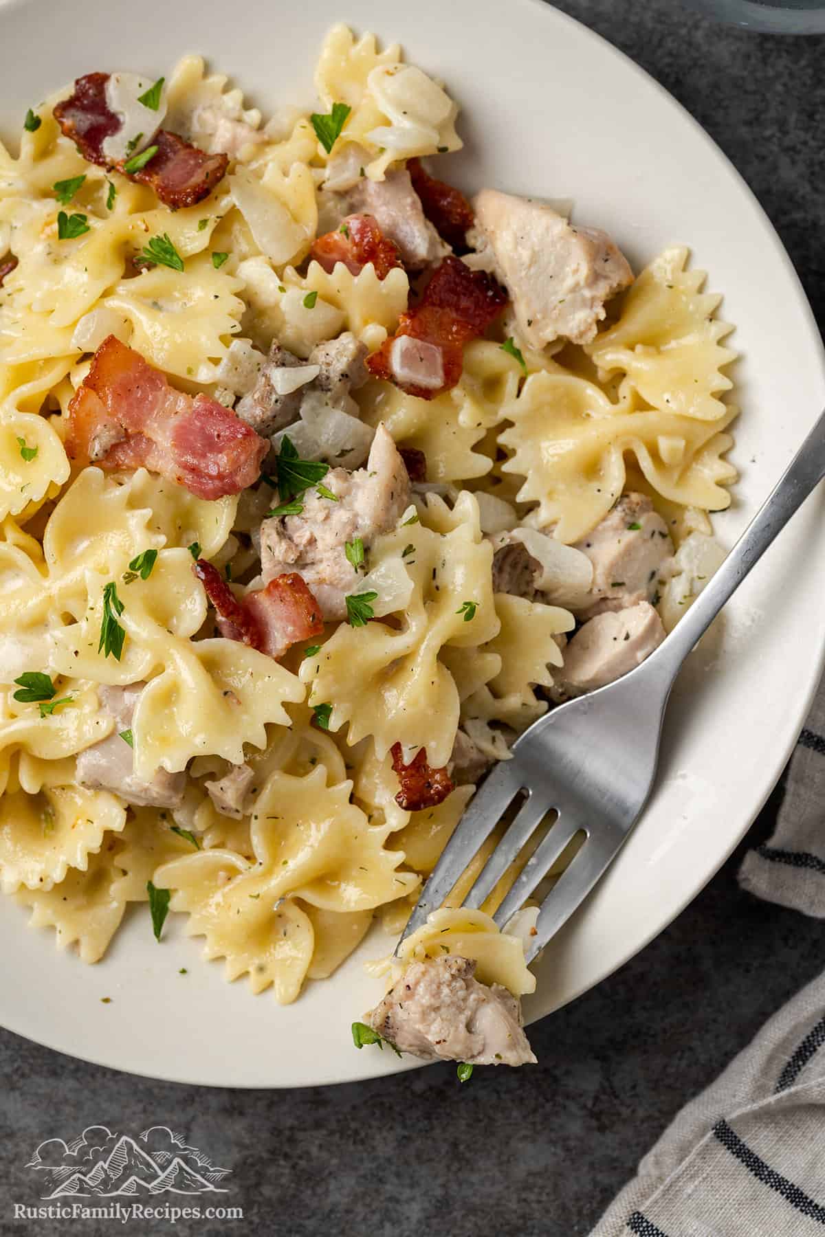 Chicken bacon ranch pasta on a white plate with a fork