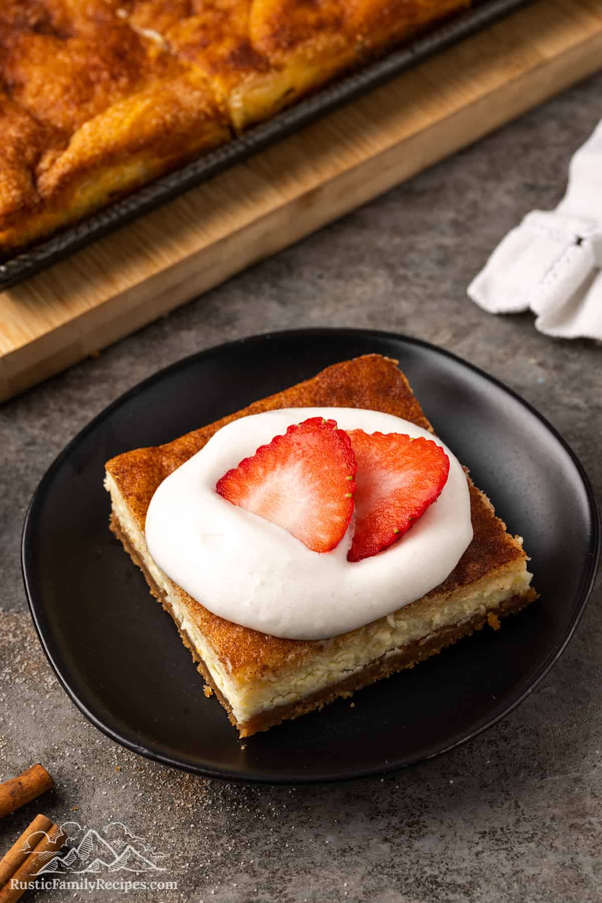 A slice of churro cheesecake topped with whipped cream and sliced strawberries
