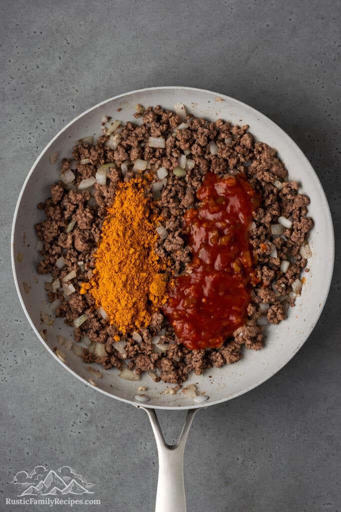 Mixing cooked ground beef with seasonings and salsa