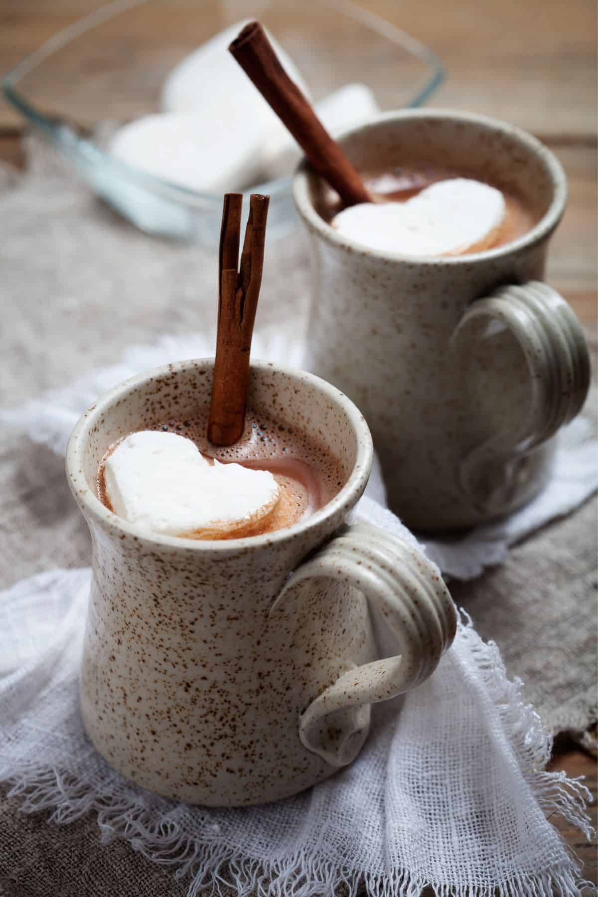 Two mugs of hot chocolate with marshmallows shaped like hearts