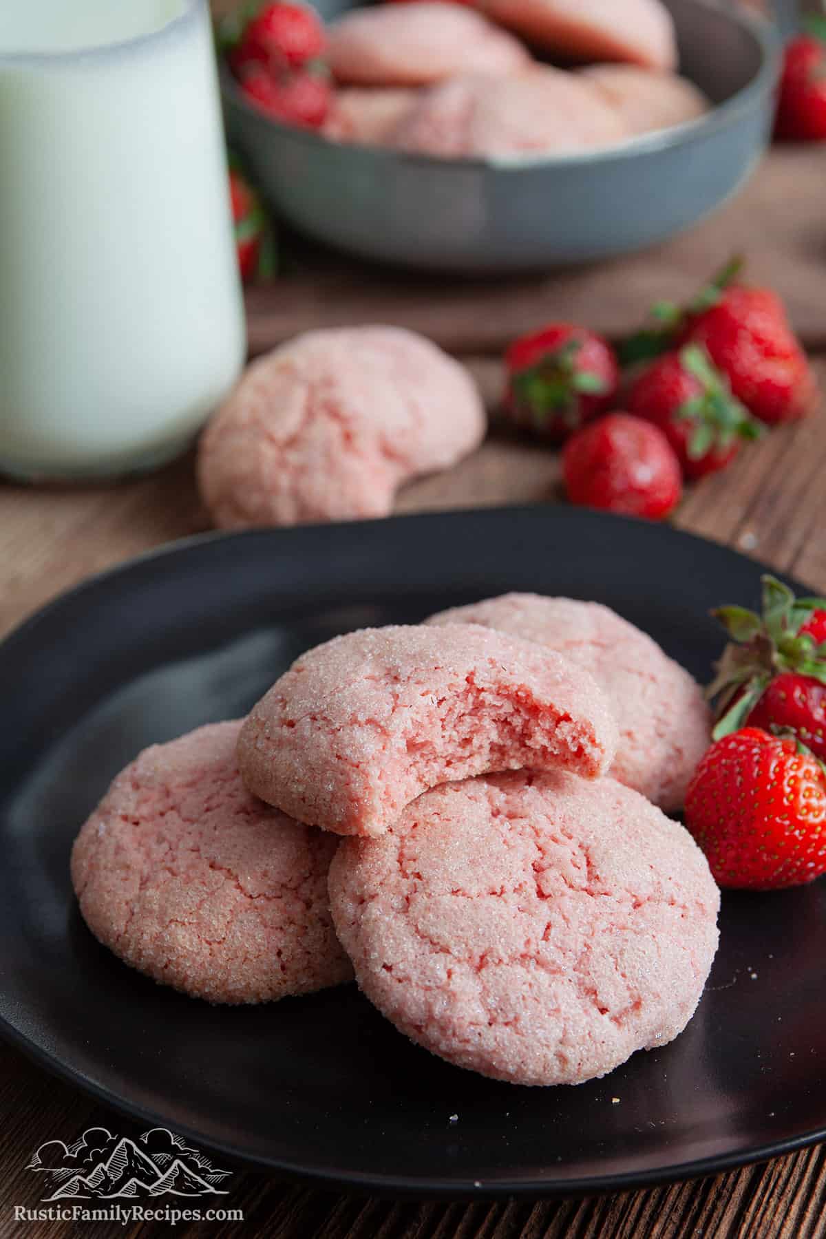 strawberry cookies on a plate with a bite taken out of one