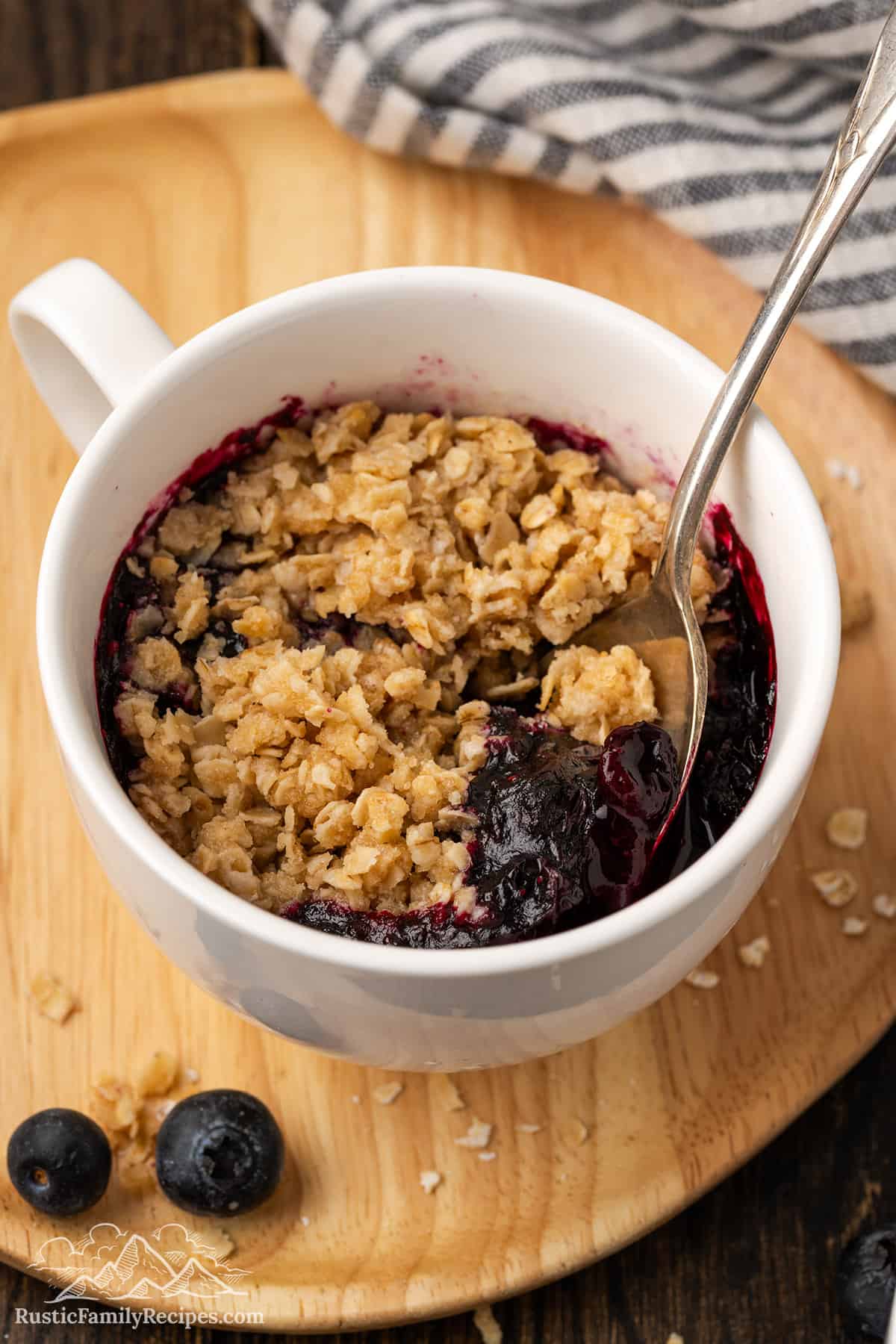 Cooked Blueberry Crisp in a mug with a spoon