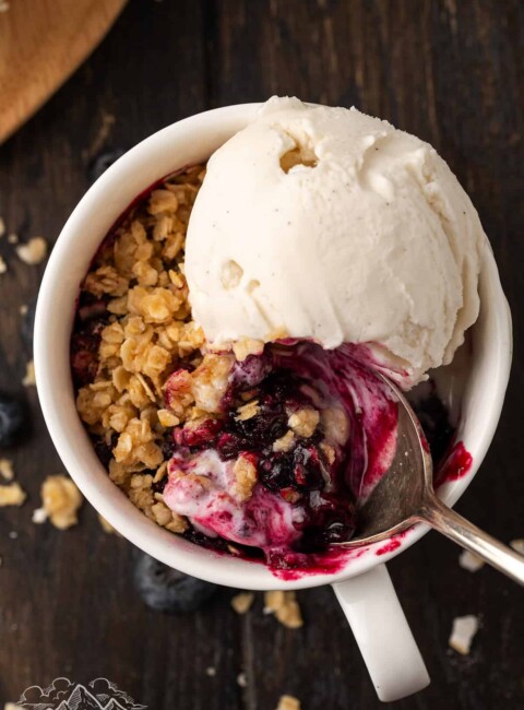 Top view of a blueberry crisp in a mug with ice cream
