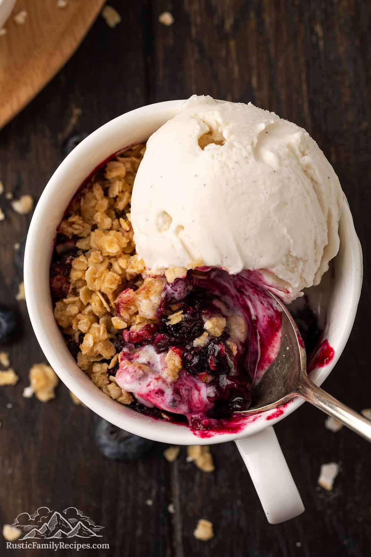 Top view of a blueberry crisp in a mug with ice cream