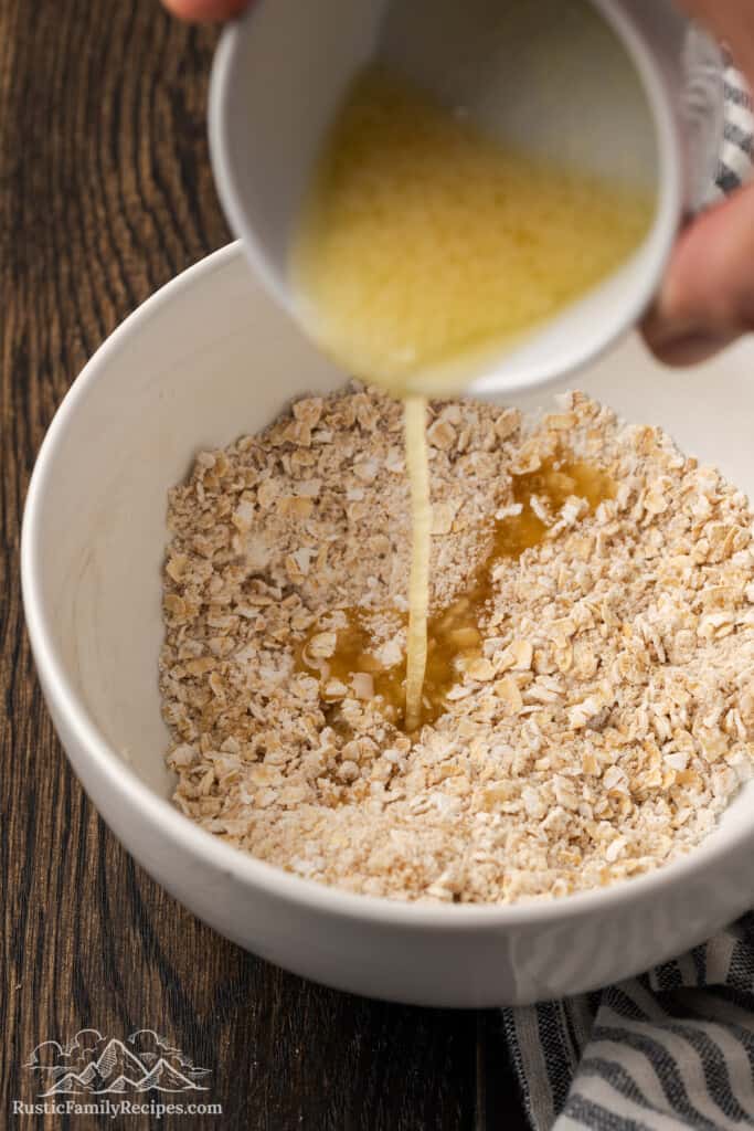 Pouring butter into the crisp topping ingredients.