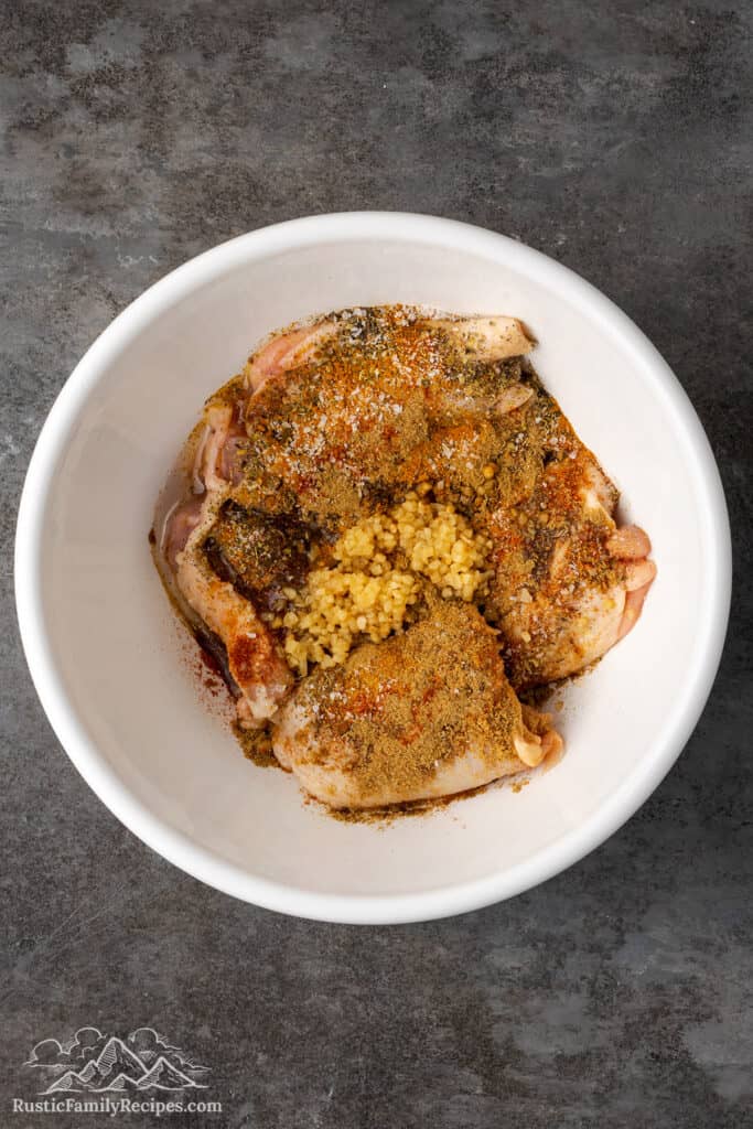 Chicken with spices and garlic in a white bowl.