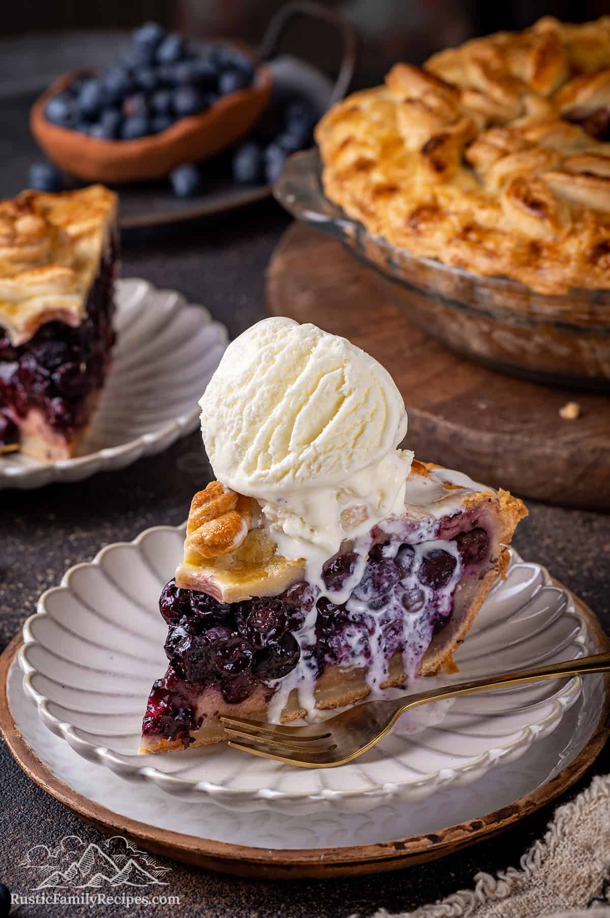 A slice of blueberry pie with a big scoop of ice cream on top