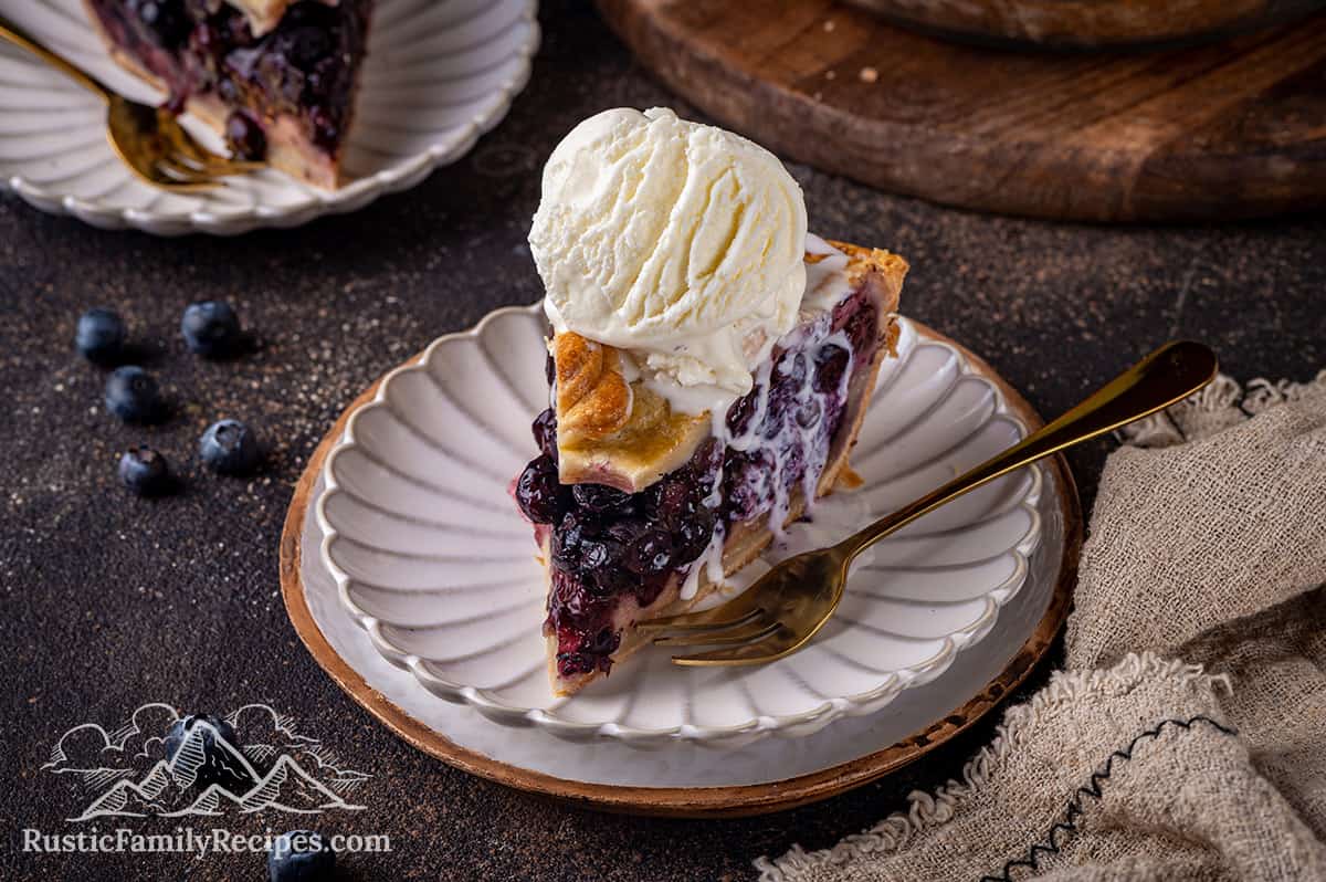 Slice of blueberry pie with ice cream on top