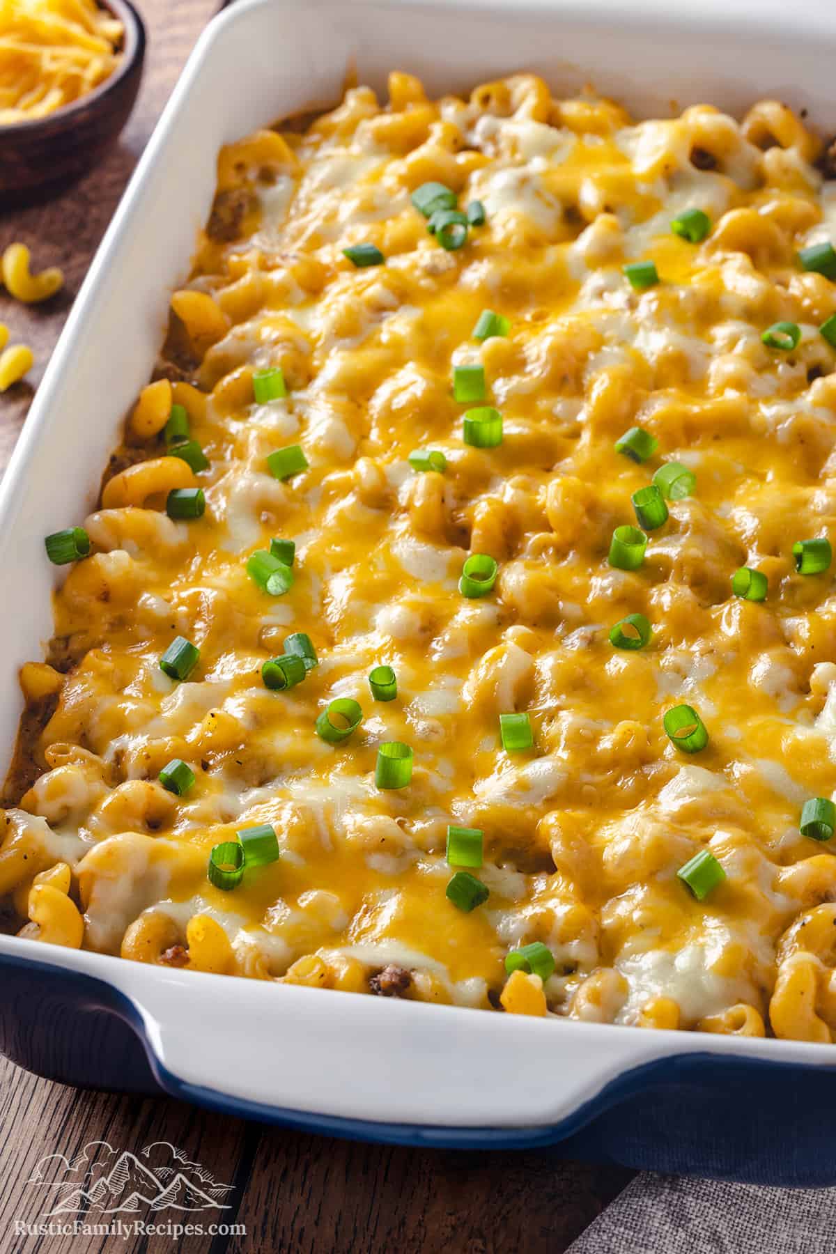 Cheeseburger casserole in a baking dish topped with melted cheese and sliced green onions.