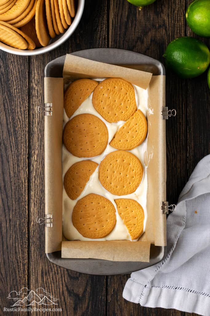 Marias cookies layered over the sweetened condensed milk mixture in a lined loaf pan.