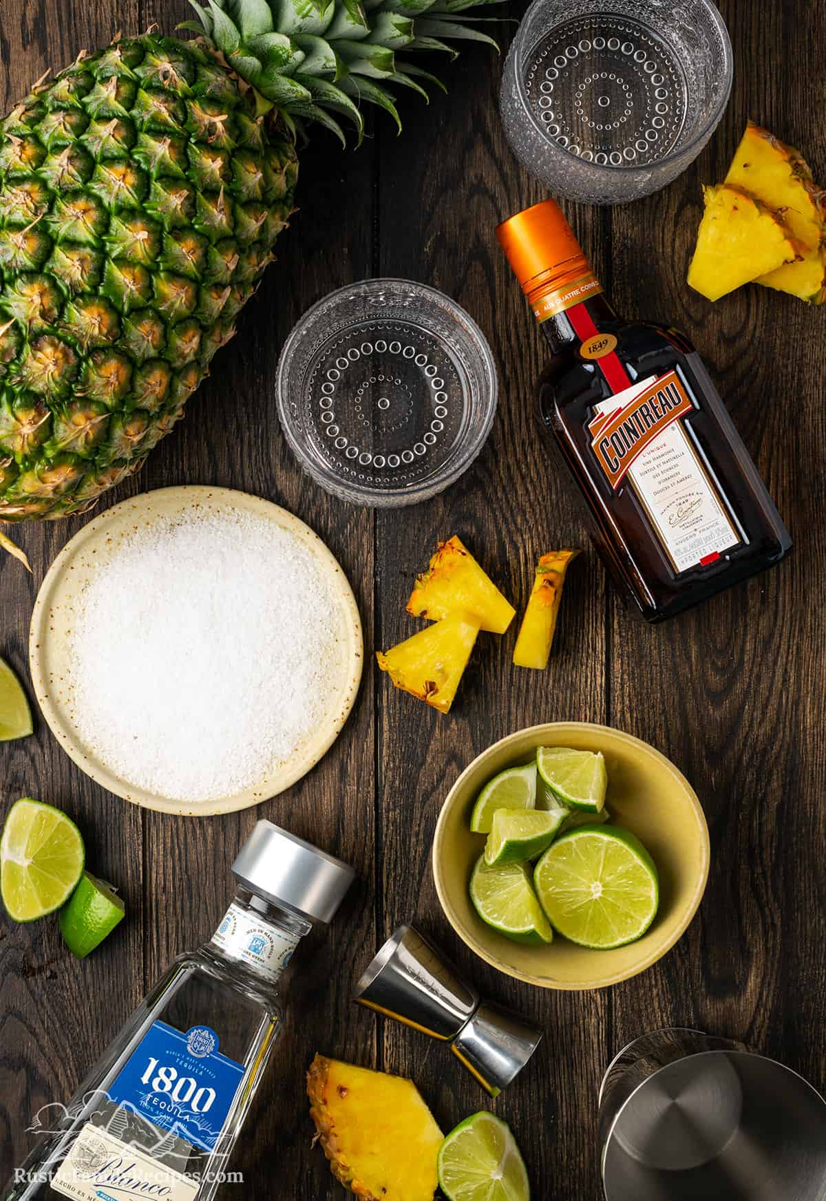 Ingredients for a pineapple margarita on a wood table