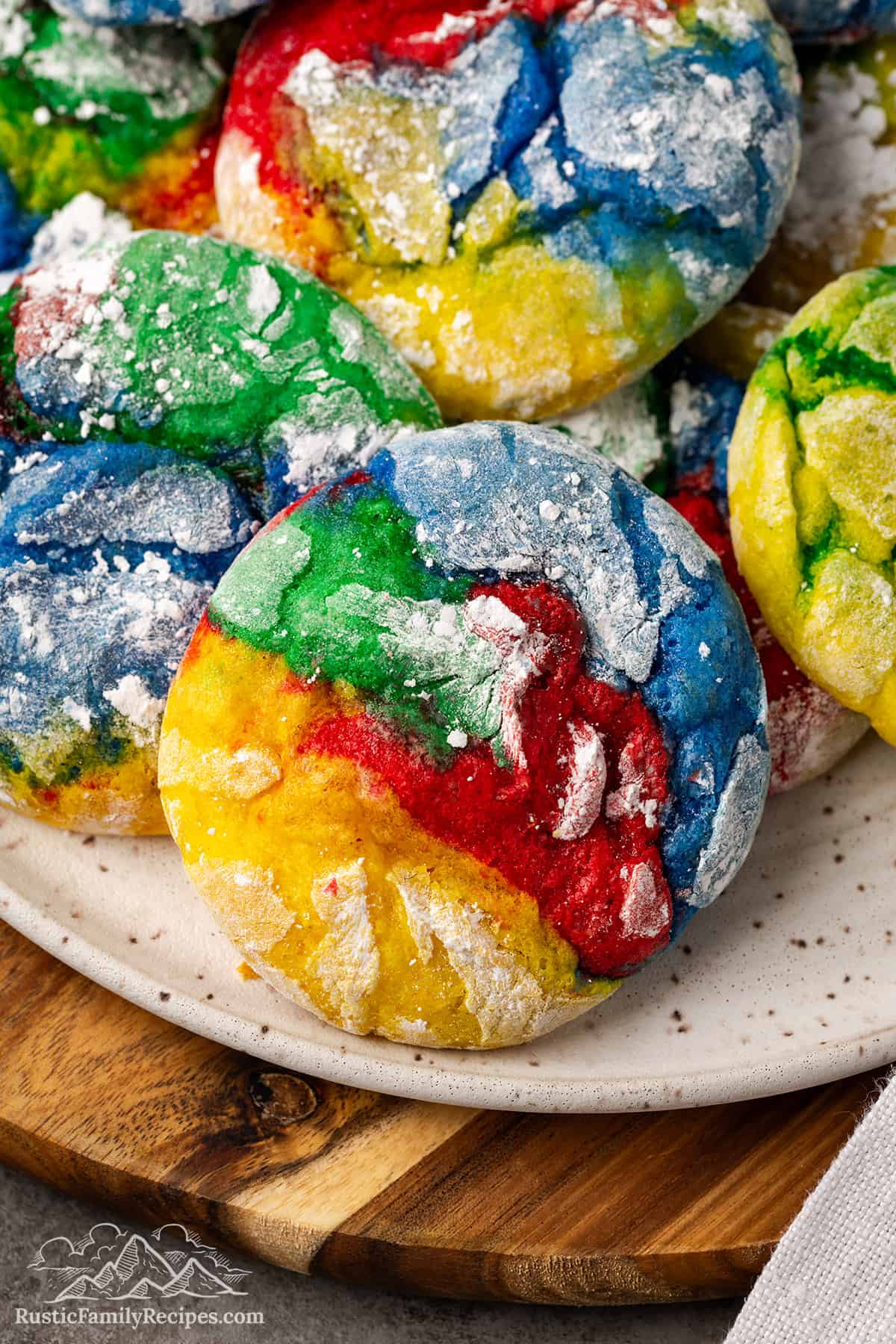 This Cool Whip Cookies recipe makes soft and chewy cake-mix cookies! You can add rainbow colors with food coloring, or make plain cookies. Close up of rainbow cool whip cookies on a plate