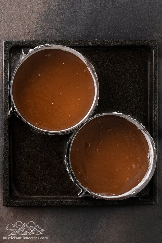 Two round cake pans filled with chocolate cake batter.