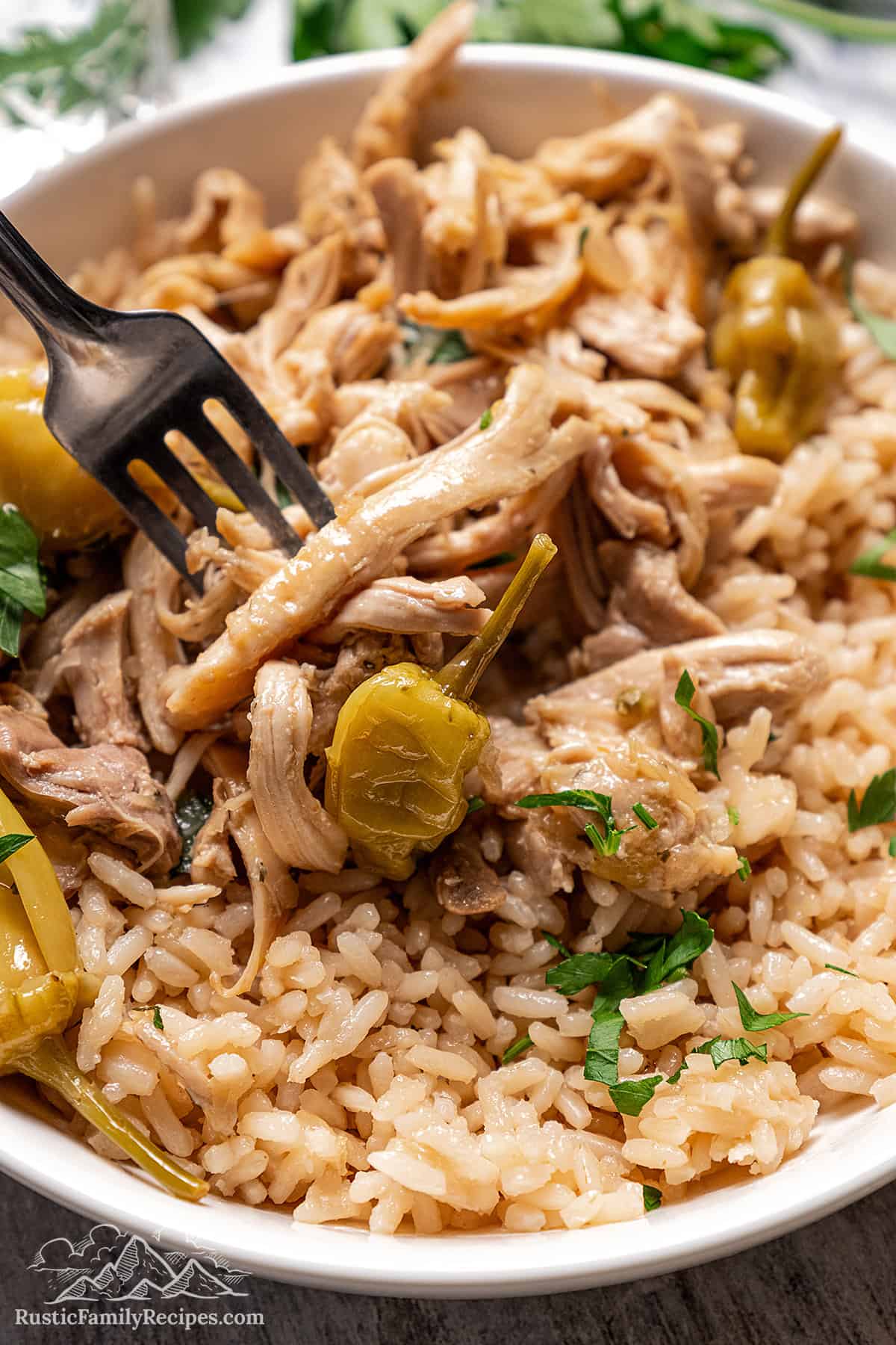 Shredded Mississippi Chicken is served over rice in a white bowl. 
