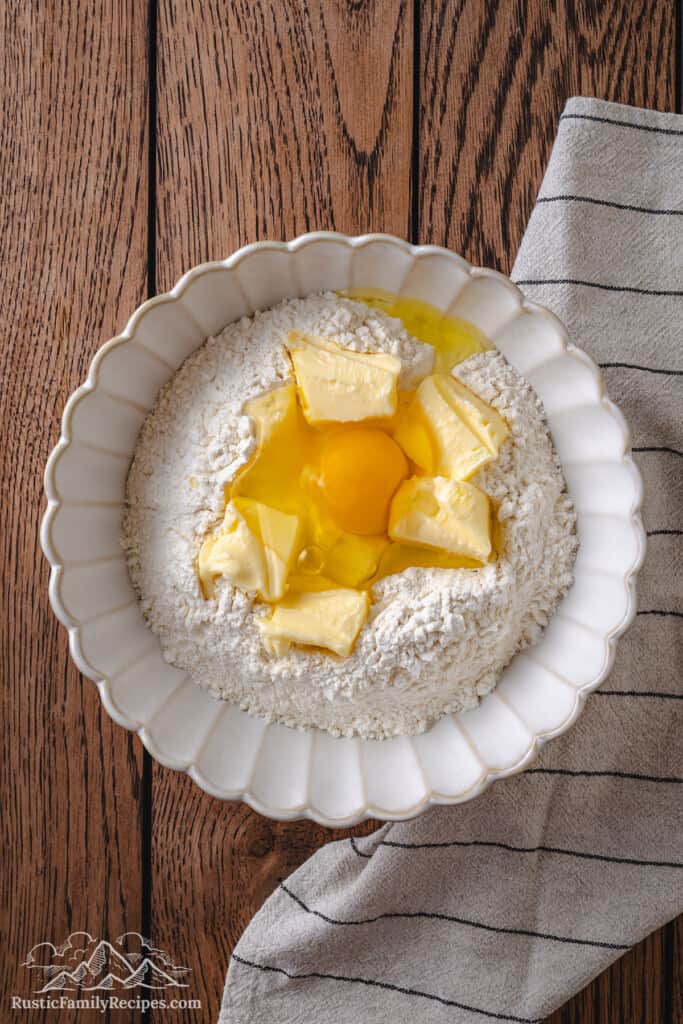 Softened butter and an egg added to a bowl of sifted dry ingredients.