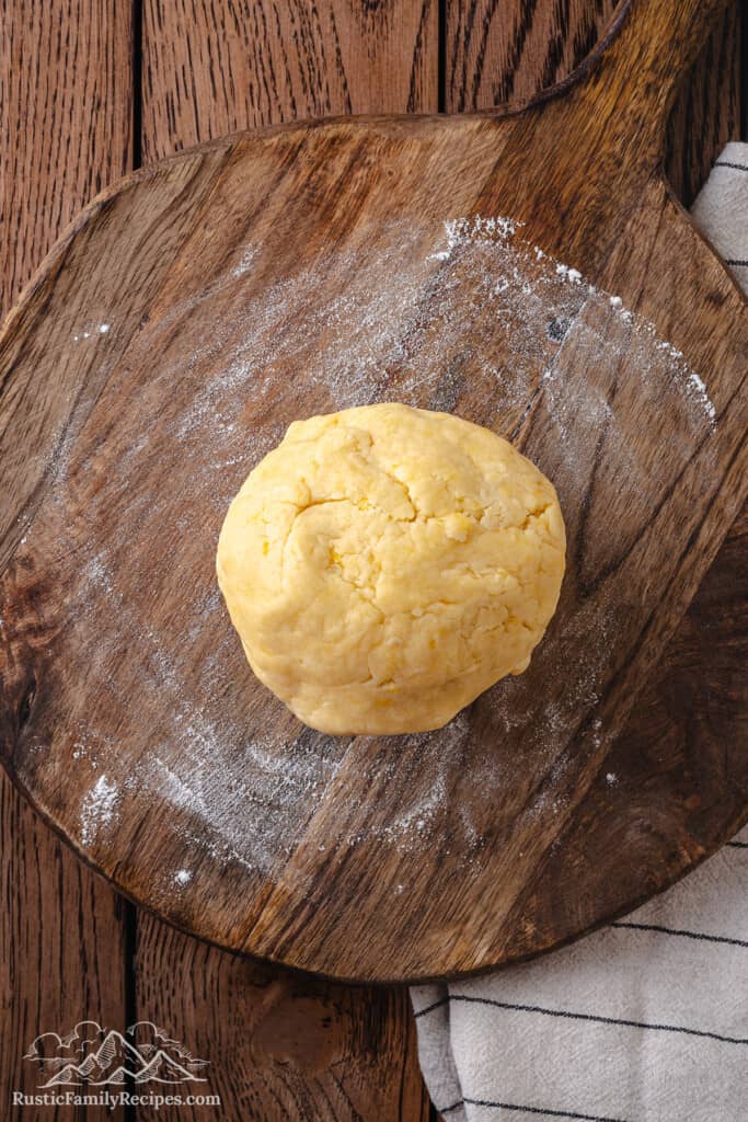 Pizzicati cookie dough formed into a ball on a wooden surface.