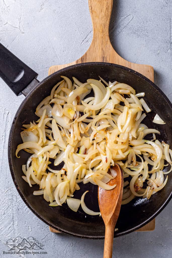 Onions in a skillet with a wood spoon