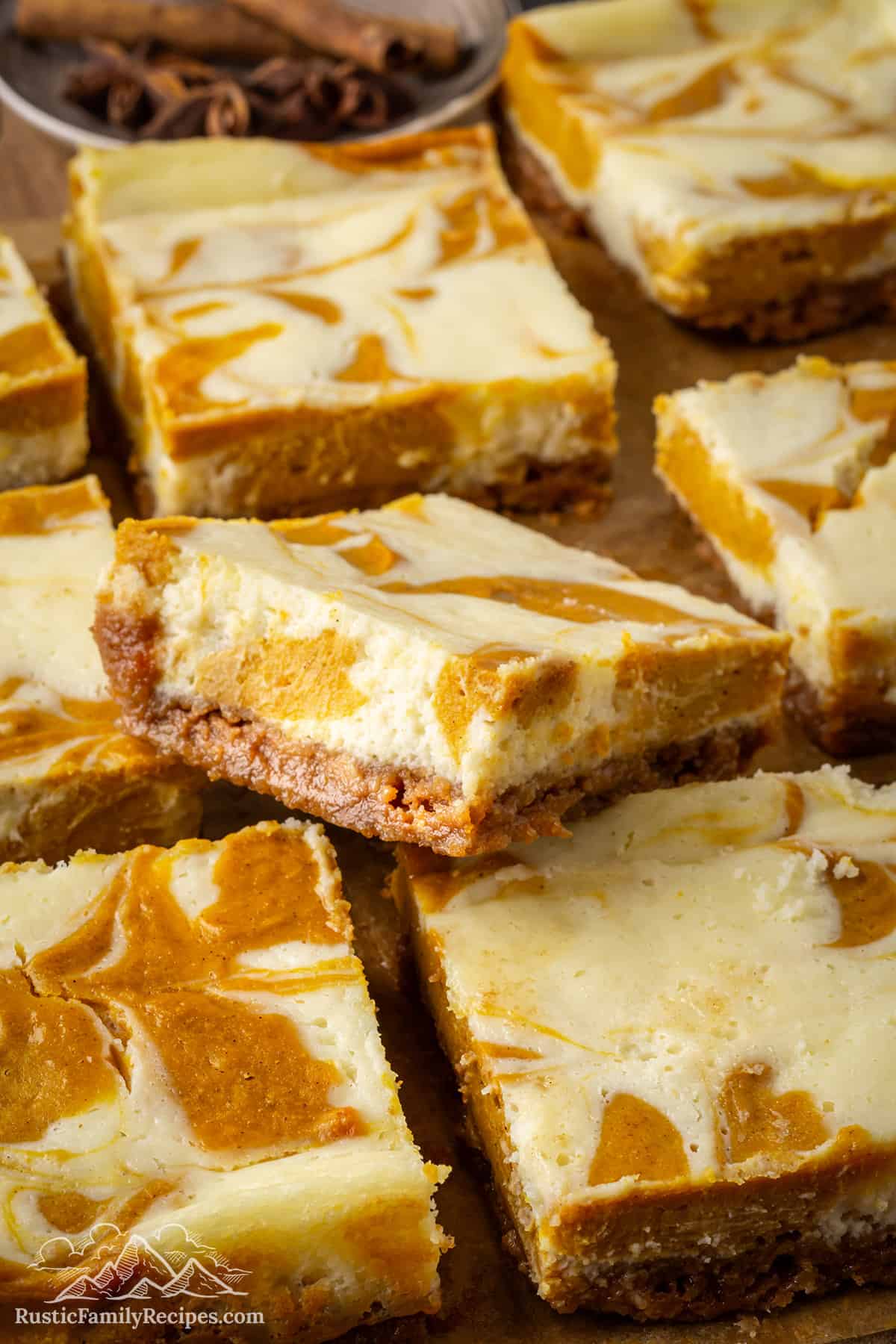 Close up of pumpkin cheesecake bars on a wooden cutting board.