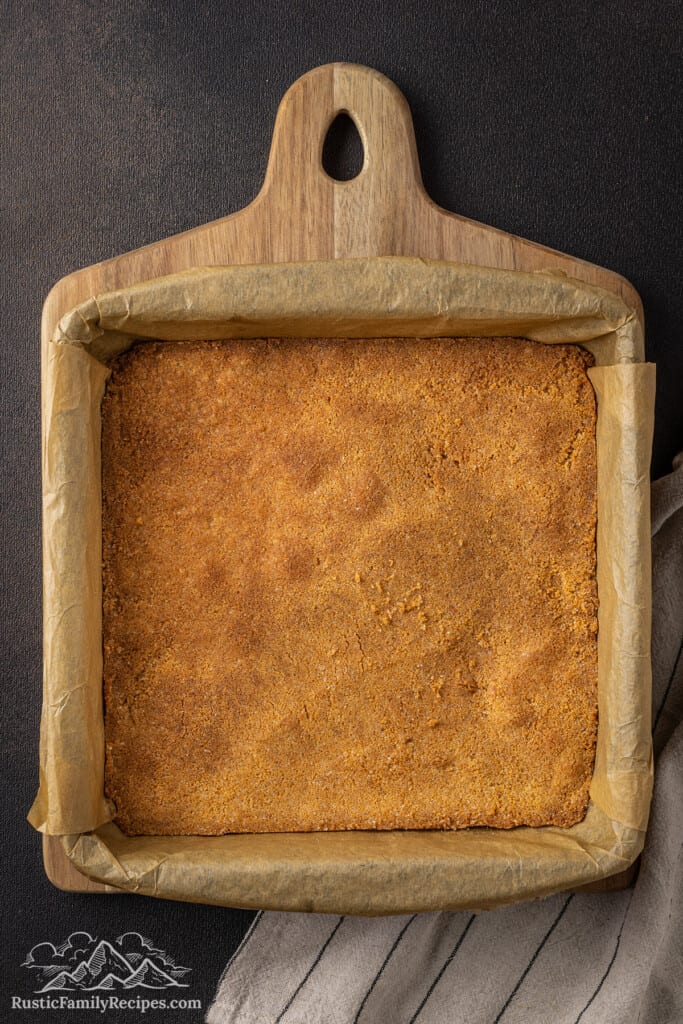 Par-baked graham cracker crust in a parchment-lined 9x9 baking pan.