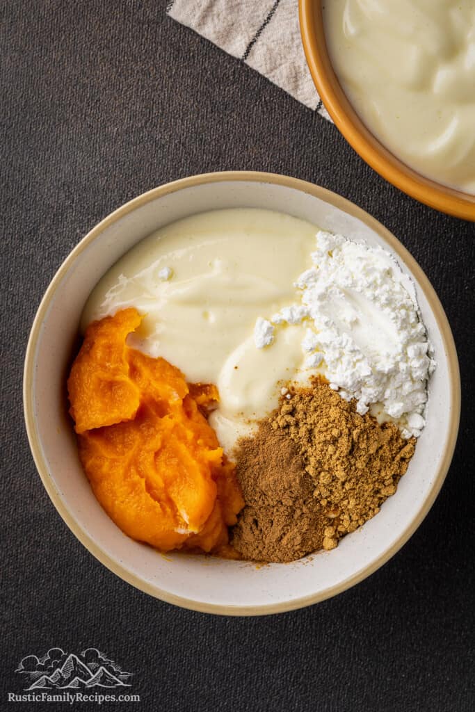 Pumpkin cheesecake filling ingredients combined in a mixing bowl.