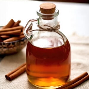 A jar of homemade cinnamon syrup next to cinnamon sticks