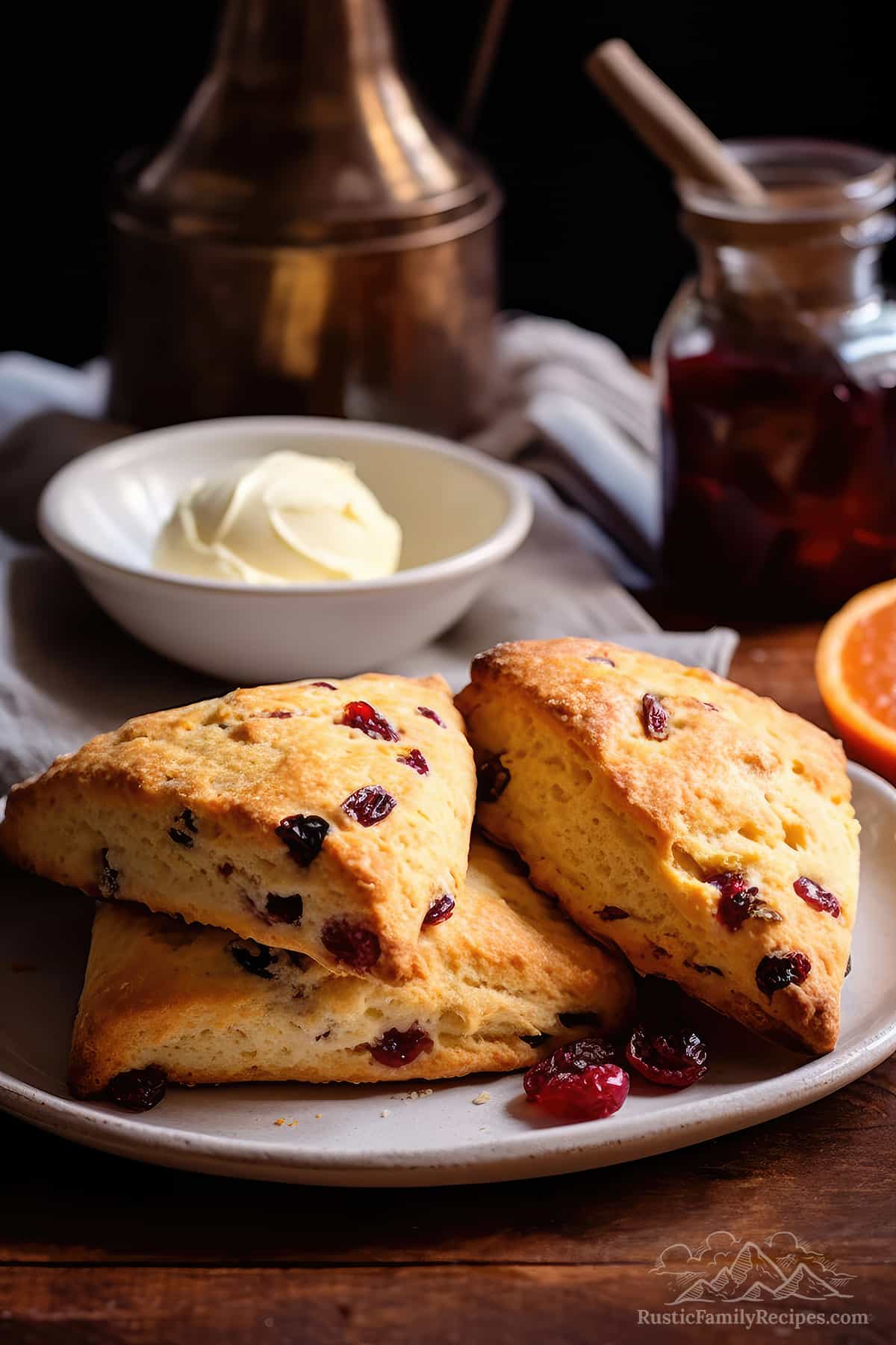 A plate of homemade cranberry orange scones with some butter in the background