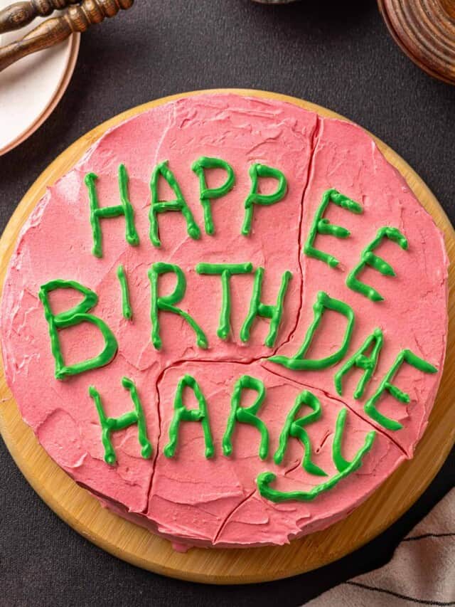 Overhead view of a Harry Potter birthday cake frosted with pink frosting and "Happy Birthday Harry" written on top with green icing.