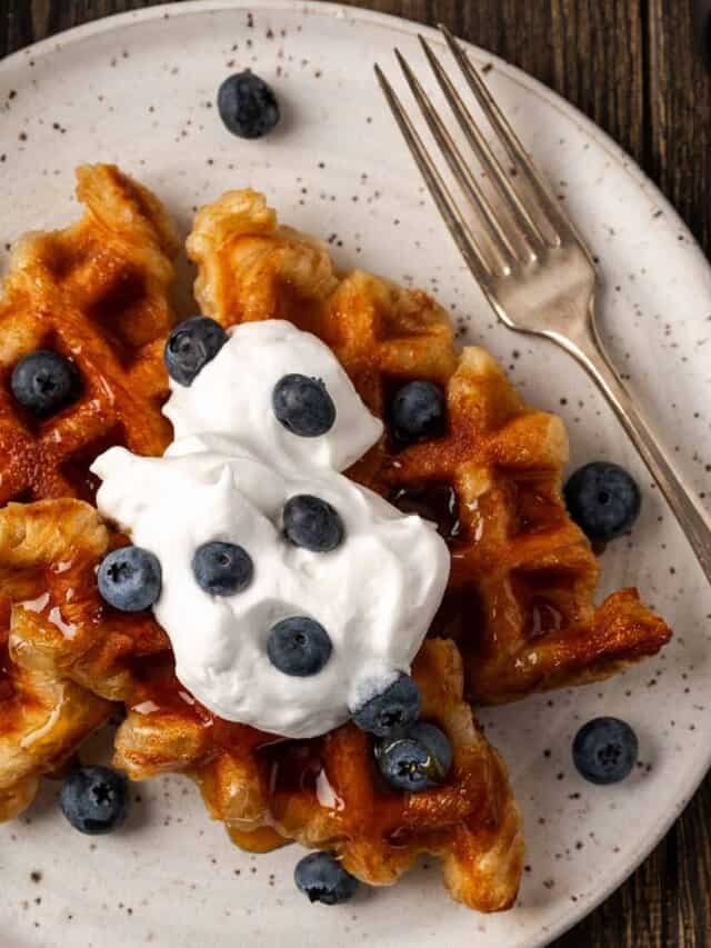 Two view of two croffles on a plate with whipped cream and berries