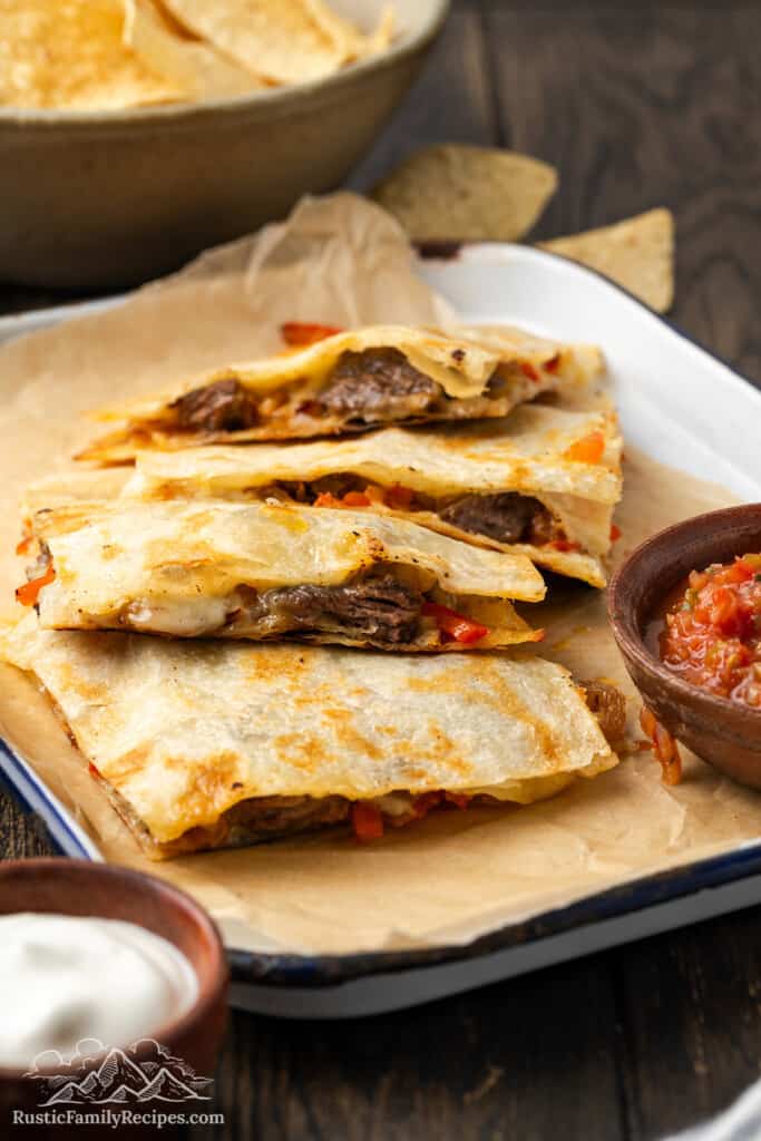 Cut steak quesadilla on a baking sheet with parchment paper and salsa