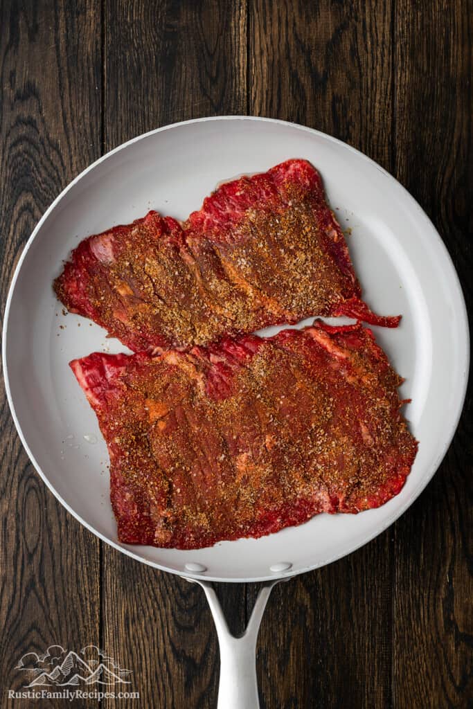 Raw steak covered with seasonings ready to cook