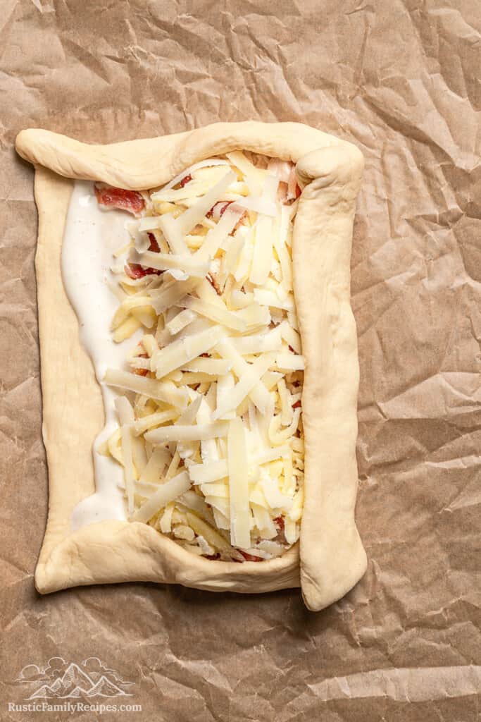 A dough rectangle partially folded over the filling for a homemade chicken bake.