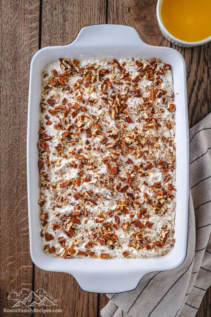 Sprinkling pecans on top of the cake mix.