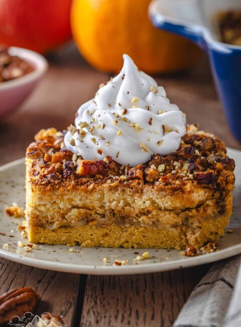 Slice of pumpkin crunch cake topped with whipped cream.