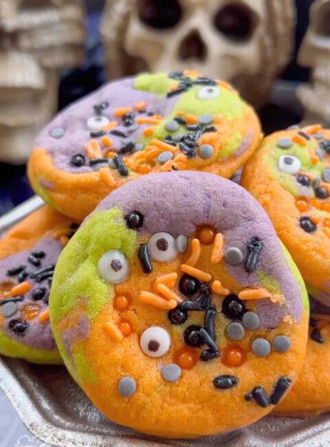 Close up of a pile of orange, purple and green hocus pocus cookies with sprinkles