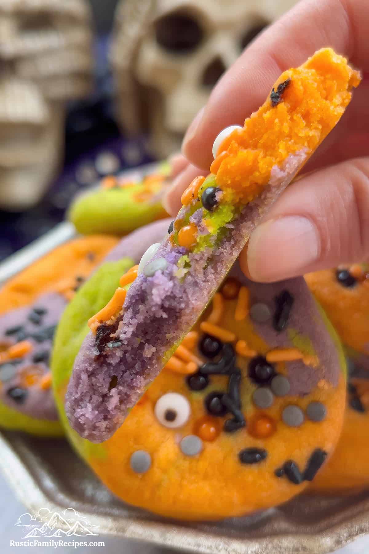 Close up of a hand holding a Hocus Pocus cookie with a bite taken out.
