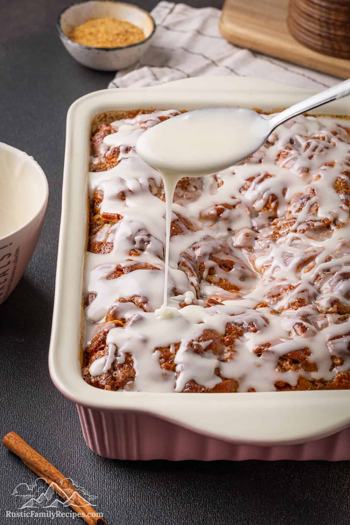 Spoon drizzling icing on a cinnamon roll casserole
